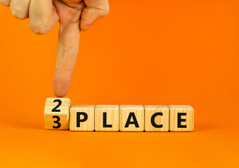 From 3 to 2 place symbol. Businessman turns wooden cubes and changes concept words 3 place to 2 place. Beautiful orange table orange background. Business and from 3 to 2 place concept. Copy space.
