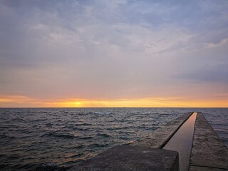 View of the Black Sea from the beach of Odessa (Ukraine). Calm sea, a seagull sits on a breakwater against the backdrop of dawn over the water. Tourist place, recreation area
