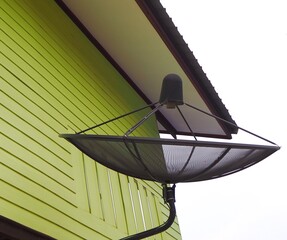 Dish antenna for receiving radio waves via satellite with home in countryside