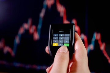 Close up hand enter the password on cryptocurrencey hardware cold wallet on stock market graph background. Secure cryptocurrency storage