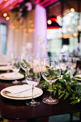 Beautiful modern wedding table decoration.  on the festive tables are flower arrangements, candles, plates with napkins, glasses and cutlery