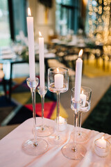 Beautiful modern wedding table decoration.  on the festive tables are flower arrangements, candles, plates with napkins, glasses and cutlery