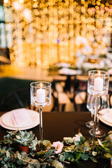 Beautiful modern wedding table decoration.  on the festive tables are flower arrangements, candles, plates with napkins, glasses and cutlery