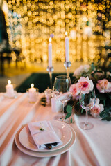 Beautiful modern wedding table decoration.  on the festive tables are flower arrangements, candles, plates with napkins, glasses and cutlery
