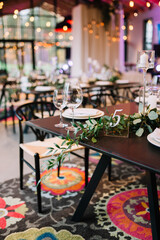 Beautiful modern wedding table decoration.  on the festive tables are flower arrangements, candles, plates with napkins, glasses and cutlery