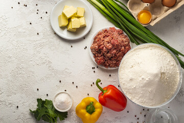 Culinary essentials neatly arranged on a textured surface, highlighting butter cubes, raw eggs, and fresh produce.