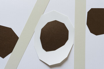 paper pieces on a flat paper surface (irregular brown and white shapes and paper stripes)