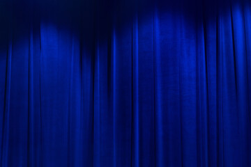 Blue brightly movie theater curtains with spotlight.