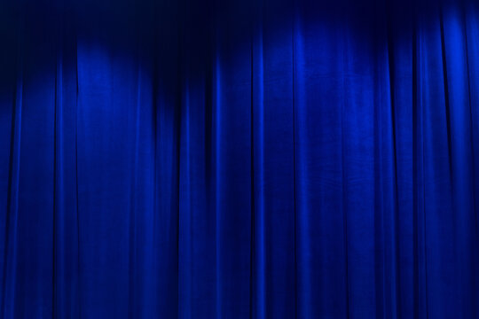 Blue brightly movie theater curtains with spotlight.
