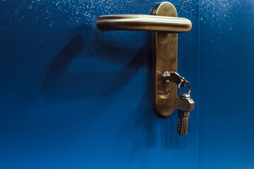 Close up photo of door lock with keys in it on the blue door