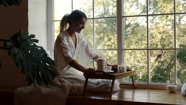 Attractive peaceful dreamy woman holding cup enjoy favourite tea drink morning invigorating coffee beverage while sit at desk in modern living room before start work. Break, pause, daydreaming concept