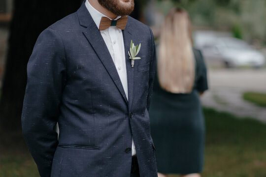  Close up of groom in blue wedding suit with boutonniere with flowers on lapel and wooden butterfly