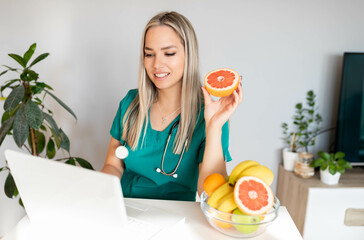 Female nutritionist with fruits working at her desk. Smiling nutritionist in her office, she is showing healthy vegetables and fruits, healthcare and diet concept. 