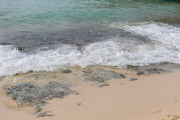 A sea wave runs onto the shore and breaks on small rocks.A fragment of the seashore with rocks covered with algae.Beautiful color of water in the Caribbean Sea of the Dominican Republic