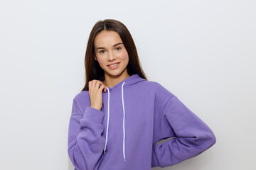 an emotional woman stands on a white background in a purple tracksuit slightly leans one hand against her face, putting the other on her belt, smiling sweetly