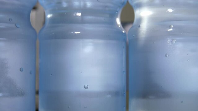 Close up of a plastic bottle filled with carbonated mineral water. Floating bubbles. Conveyor line of the food industry.