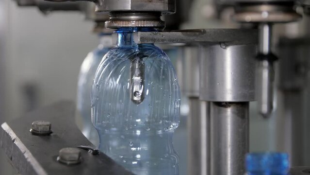 Close-up of pouring water into a plastic bottle with a volume of 0.5 liters in the filling unit. Shop for the production of mineral water and soft drinks.