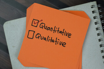 Concept of Quantitative or Qualitative write on a sticky notes isolated on Wooden Table.