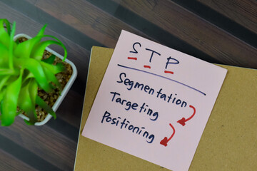 Concept of STP - Segmentation Targeting Positioning write on sticky notes isolated on Wooden Table.