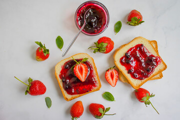 Strawberry jam in a glass of bread on an old background