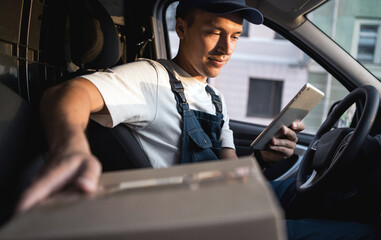 The driver in the uniform of the courier company fast delivery of goods to the house.