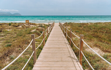 Obraz premium Wooden platform through the sand dunes leading to the beach of the sea