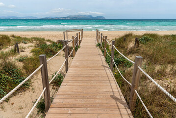Fototapeta premium Wooden platform through the sand dunes leading to the beach of the sea