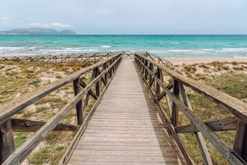 Wooden platform through the sand dunes leading to the beach of the sea