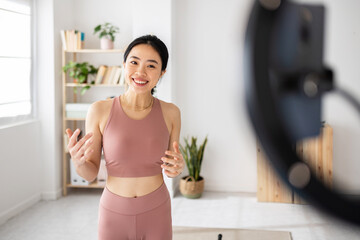 Fitness asian young woman recording online class in the living room - Cheerful female influencer streaming on social media about wellness exercise at home - Millennial content creator people concept