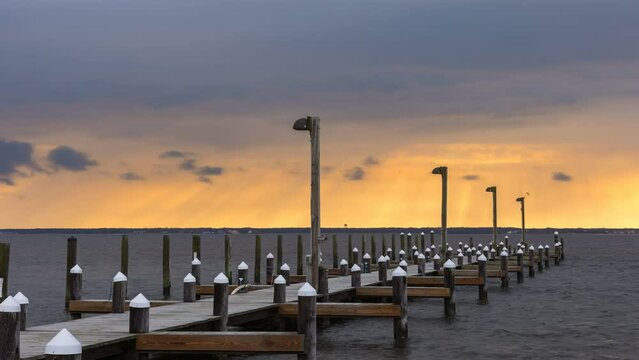 Time lapse of storm clouds getting lit up with sunset colors over a marina. Island Beach State Park New Jersey