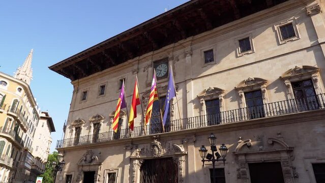 Facade of Town hall of Palma de Mallorca with Flags of Spain, Balearic Islands, Catalonia and European Union waving in the wind - Spain