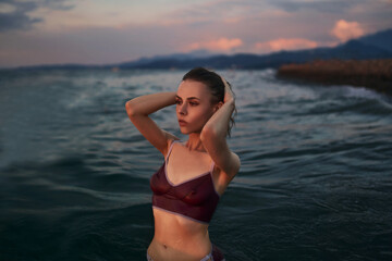 Gorgeous slim model in a violet swimsuit is posing in the water.