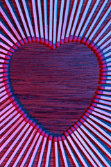 Matches on a wooden background form abstract heart. Neon light. Copy space for text. Passionate hot...