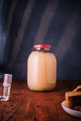 Jar of homemade bread kvass on wooden background. Empty glass, slices of bread. Traditional slavic...