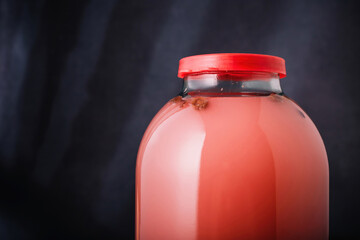 Jar of homemade bread and hibiscus kvass on wooden background. Traditional slavic beverage kvas,...