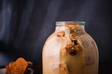 Jar of homemade bread kvass, bread slices on wooden background. Process of making of traditional...