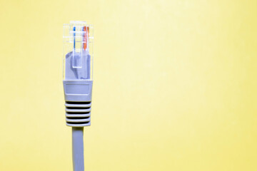 Gray RJ45 Ethernet network cable. light yellow background