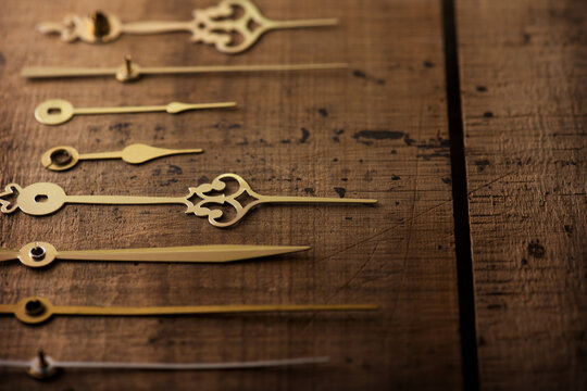 Clock hands or needle aligned on old wooden surface. Time concept image. Focus on center needle. Shallow depth of field.
