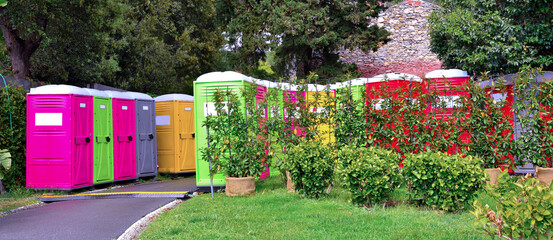 Portable colored mobile toilets in the park. A line of chemical toilet cubicles for the euroflora...