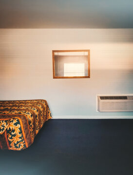 A dramatic interior view of a budget hotel room with window reflection.
