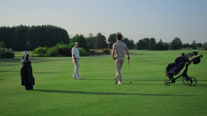 Active men enjoy golf on course field. Two golfers teeing play sport outside.