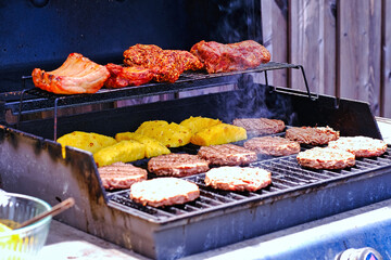 Cooking yummy meat ribs pineapple on hot grill with smoke. Summer backyard family bbq party background.