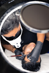 cosmetologist painting a man's eyebrows with micropigmentation procedure