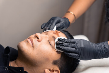 stylist cleaning a man's eyebrows after treatment