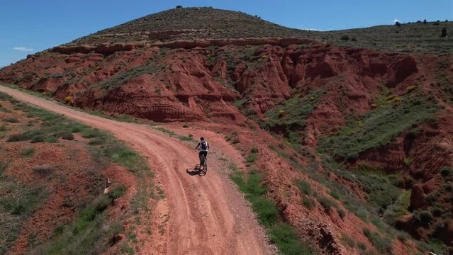 Man riding a BTT following a sand path in a red dessert in Teruel, Spain.