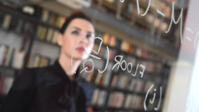 Time lapse of a smart educated female in the Blockchain industry writing a mathematical formula on glass