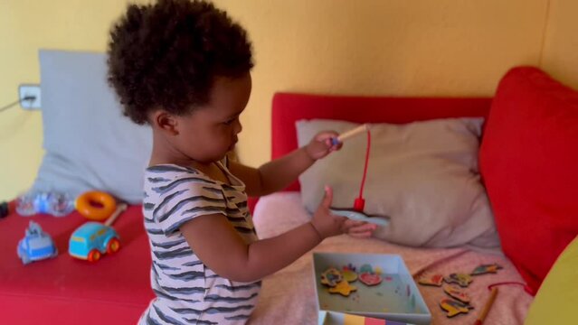 Cute two year old afro european child playing with a magnet game to fish