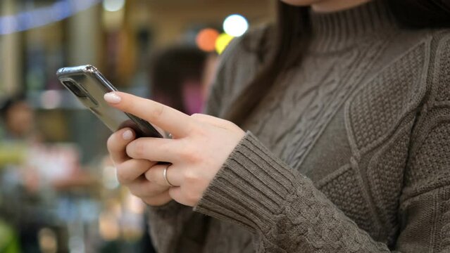 Shopping center. Moll. Finger of woman touching scroll page app on mobile phone. Browsing movie video in the internet library to watch film online.