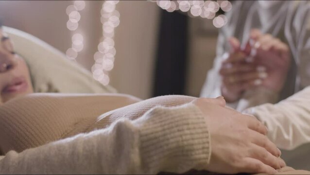 Pregnant woman and midwife stroking and touching belly. Woman preparing for childbirth at home with doula, feeling pain, having contractions. Motherhood, medicine, pregnancy concept