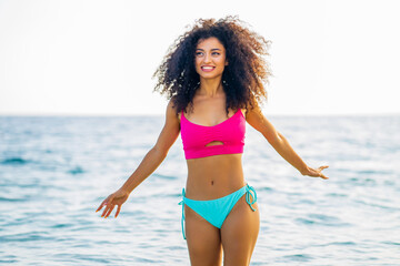 multicultural race smiling curly woman in swimming suit standing at the beach